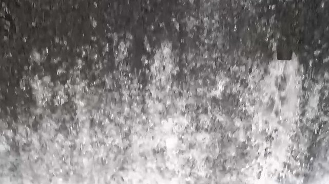 Slow motion close-up of crystal clear water flowing and creating powerful white foam splashing surface