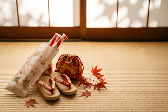 七五三の千歳飴 紅白の飴袋と草履・巾着を並べた和室 秋の日差し 右側に余白