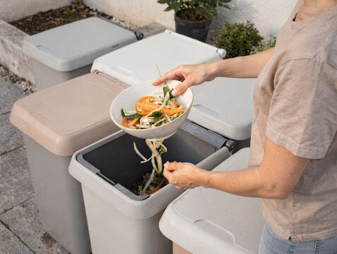 Adult Separating Kitchen Scraps at Household Composting Station