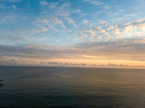 Calm ocean at dusk with pastel clouds and orange horizon