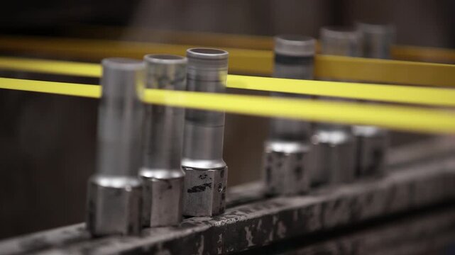 Closeup view of yellow PET strap production on cooling rollers.