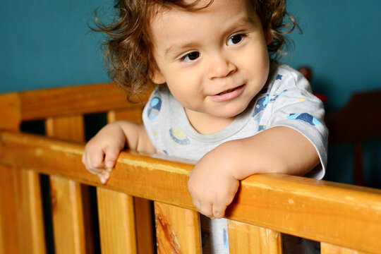 Curly toddler standing in the crib.