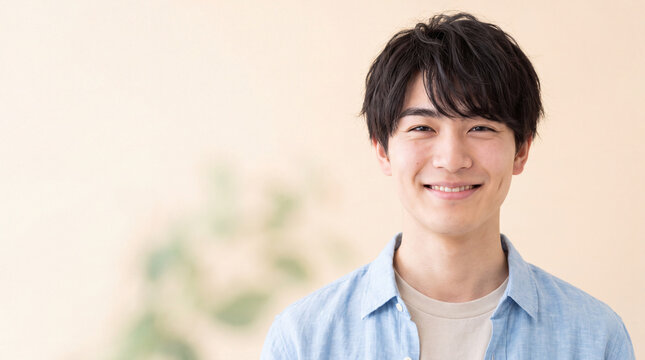 明るい背景の前で人懐っこい笑顔を見せる爽やかな若い男性 | 自然な笑顔