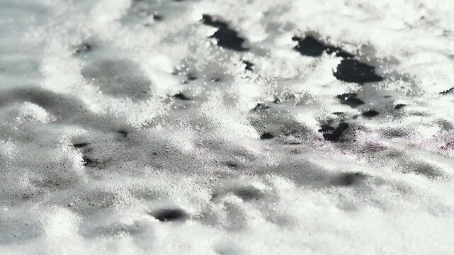 Foam receding over black pebbles close up in Iceland