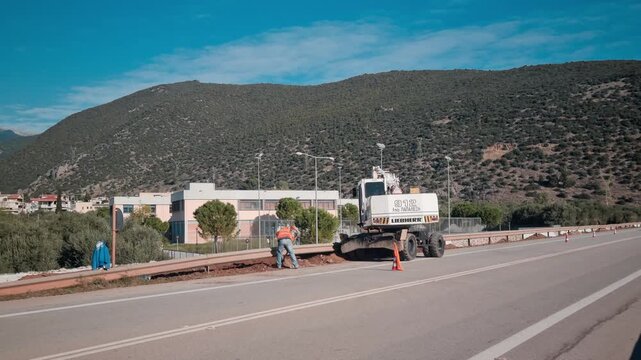 Real Time Video of Heavy Excavator and Construction Worker Doing Roadside Maintenance