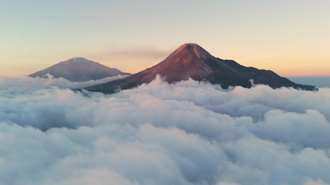 Aerial view of Mount Merapi peak rising above a sea of clouds at sunset in Indonesia