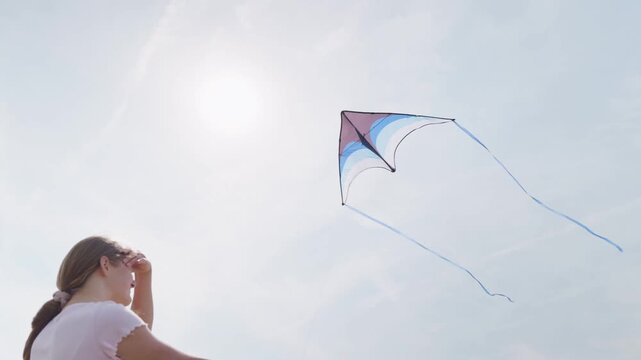 The girl looks up at the flying kite rear view close-up from below dynamic camera movement