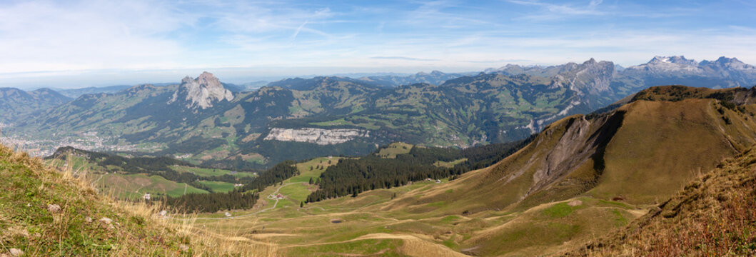 Breathtaking panoramic view of alpine mountain ranges and green valleys under a clear blue sky