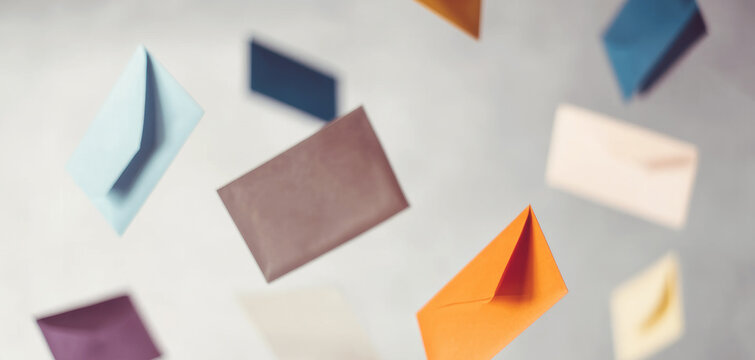 Multiple colorful envelopes flying and moving across a light background, representing the flow of information and online communication