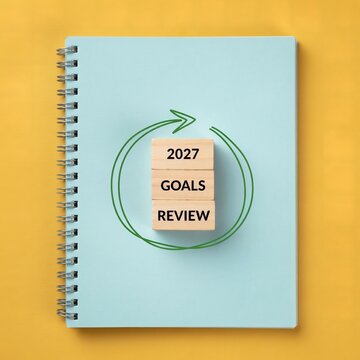 Wooden blocks spelling goals and review for year twenty twenty seven placed upon spiral notebook cover