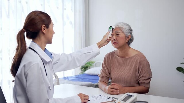 Doctor measuring temperature of elderly patient with infrared thermometer in medical clinic during health check up