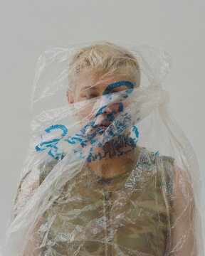 Front Facing Portrait of Person Wrapped in Transparent Plastic Bag, Concept of Plastic Pollution and Consumerism