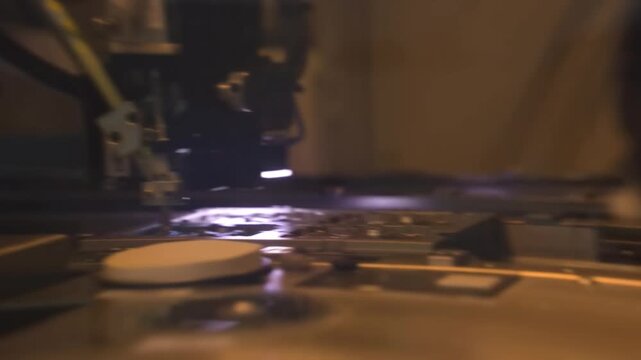 Automated dispensing needle working on smartphone circuit board. Precision machine in electronics factory