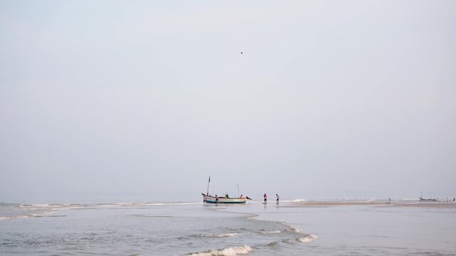 Mandrem beach landscape with fishing boat calm ocean waves and people