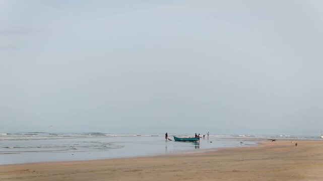 Mandrem beach scene with fishermen in a boat calm ocean waves and