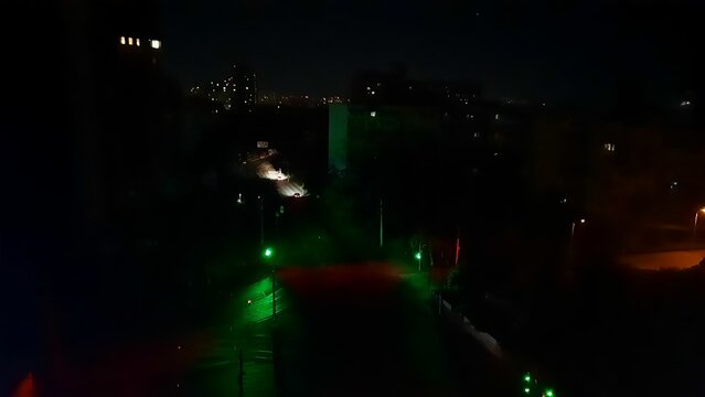 A nighttime intersection in Kyiv during a blackout following Russian strikes on energy infrastructure. All that can be seen are the lights of vehicles and traffic signals.