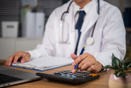 Doctor calculating healthcare costs and medical billing at desk