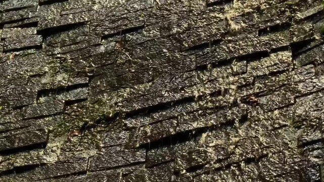Textured dark stacked stone wall waterfall as a natural decorative background