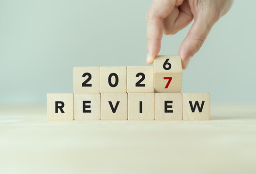 2026 to 2027 Year in Review. Annual Review. Turning wooden block from 2026 to 2027 above REVIEW letter blocks. Year-end evaluation, annual reflection, business performance, new year transition.