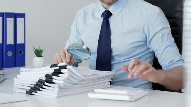 Mature businessman investigating financial documents with a magnifying glass. Performing detailed analysis. Scrutinizing reports