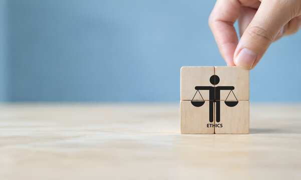Business ethics concept. Business moral principles concept. Hand holds the wooden cubes with "ETHICS" symbols on grey background and copy space. Banner for business integrity, good governance policy. 