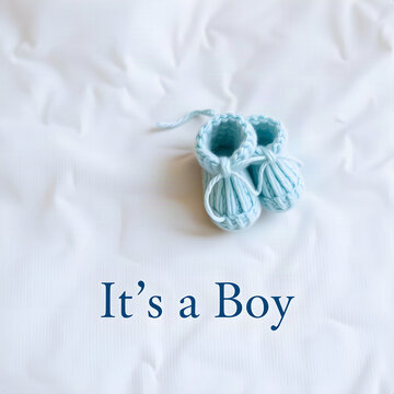 Its a Boy baby announcement banner with soft blue knitted booties on white linen