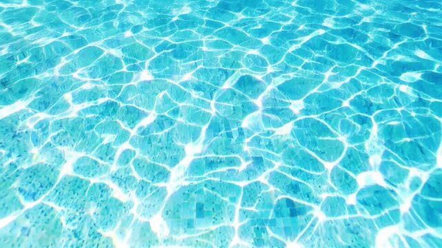 Top view of bright azure swimming pool water with sparkling sun caustics and vivid ripples on the tiled bottom, summer resort background.