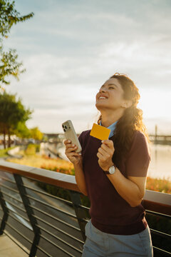 Woman enjoying successful online shopping using smartphone and credit card