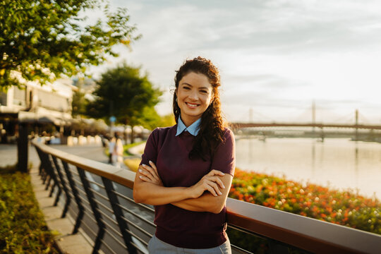 Confident young woman smiling on city river promenade