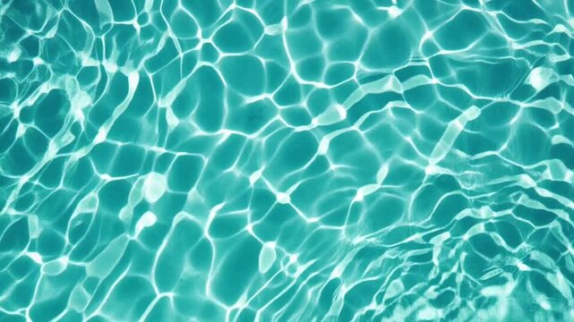 Clear turquoise swimming pool water surface with ripples and sun caustics in summer