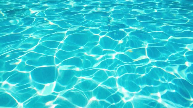 Clear turquoise swimming pool water surface with slow ripples and sun caustics in summer