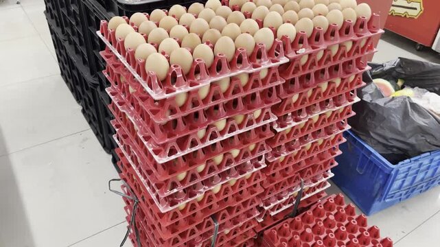 Large stack of fresh brown chicken eggs in red plastic crates at wholesale market