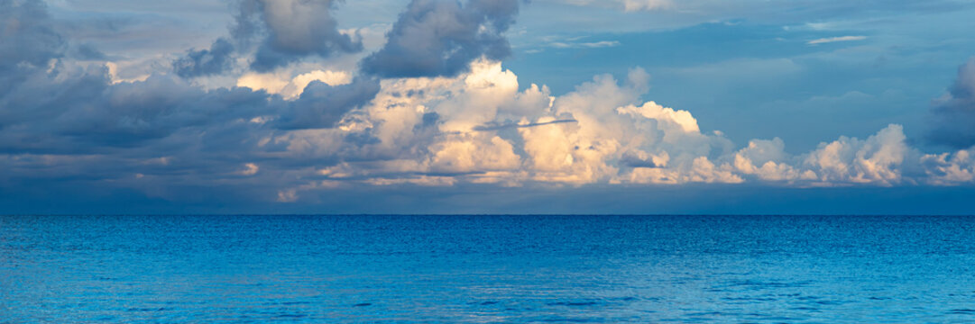 Clouds reflect on the ocean surface during late afternoon hours at a coastal location