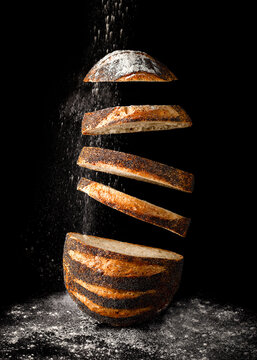 Floating Slices of Artisan Bread with Falling Flour on Black Background