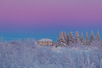 A lonely house in a winter forest at sunset. A peaceful winter landscape. © lizavetta