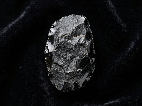 A sharp black obsidian hand axe tool from the prehistoric stone age era.