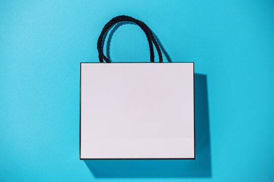 Empty white shopping bag on blue background, top view