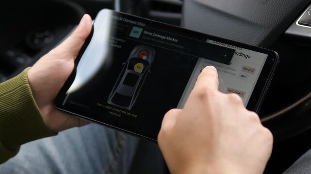Insurance assessor reviews a vehicle damage map on a tablet, repositioning defect markers and comparing repair findings during a digital auto claim inspection.
