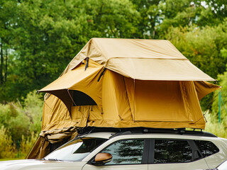 Camping gear setup on top of a car in a green landscape during daytime © Voyagerix