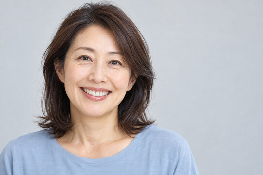 自然な白い歯を見せて微笑む五十代の日本人女性