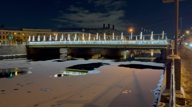 Saint Petersburg in winter.  Video of beautiful night cityscape with Semyonovsky Bridge 1857 across frozen Fontanka River in festive Christmas lighting.  Travels in New Year and Christmas holidays