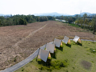 A row of white tents set up on a green lawn for camping © zhu difeng