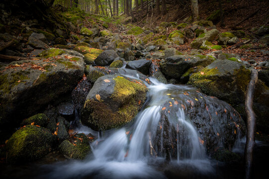 Mountain stream with silky waterfall and mossy rocks in an autumn forest   