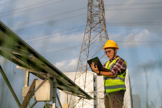 A qualified technician reviews power generation and transmission infrastructure performance on a mobile device under an open sky.