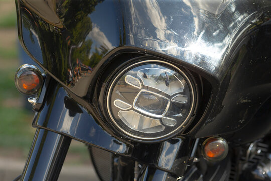 Close-up view of round headlight and black front fairing on motorcycle with chrome reflectors and turn signals visible at sides.