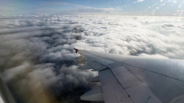 view from the window of an airplane to the wing of an airplane in clear sunny weather, flying over clouds