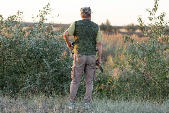 A hunter with a gun in camouflage clothing. A gentleman with a gun, medium shot, unrecognizable.