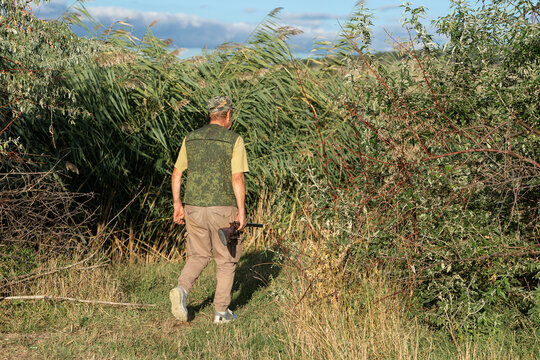 A hunter with a gun in camouflage clothing. A gentleman with a gun, medium shot, unrecognizable.