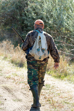 A hunter with a gun in camouflage clothing. A gentleman with a gun, medium shot, unrecognizable.