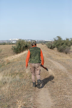 A hunter with a gun in camouflage clothing. A gentleman with a gun, medium shot, unrecognizable.